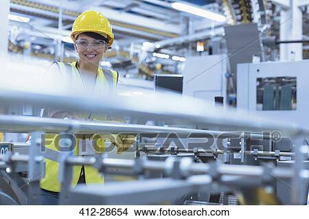 Picture - Portrait smiling female worker at machinery in factory. Fotosearch