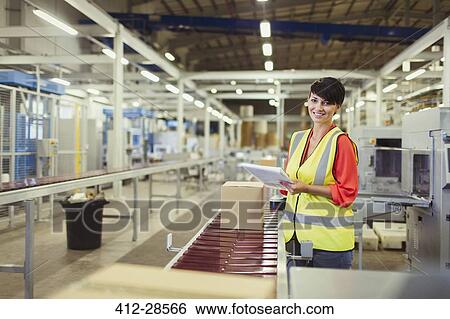 Stock Photograph - Portrait smiling worker checking cardboard boxes on conveyor belt production line in factory. Fotosearch