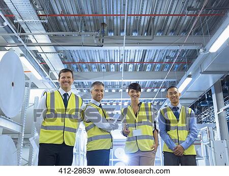 Portrait smiling workers in reflective clothing in factory View Large Photo Image Stock Photo - Portrait smiling workers in reflective clothing in factory. Fotosearch