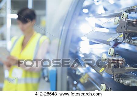 Stock Photo - Worker behind machinery in factory. Fotosearch