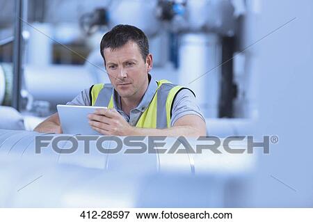 Worker using digital tablet in factory View Large Photo Image Stock Photo - Worker using digital tablet in factory. Fotosearch