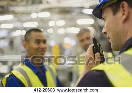 Worker using walkie-talkie in factory View Large Photo Image Stock Image - Worker using walkie-talkie in factory. Fotosearch