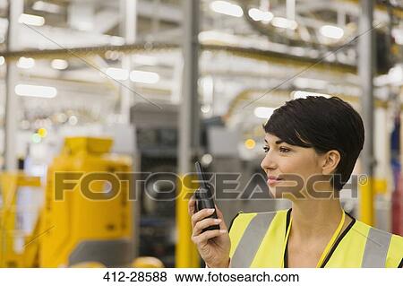 Worker using walkie-talkie in factory View Large Photo Image Stock Photo - Worker using walkie-talkie in factory. Fotosearch