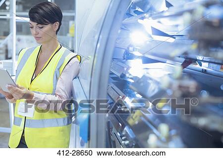 Worker with digital tablet leaning on machinery in factory View Large Photo Image Stock Image - Worker with digital tablet leaning on machinery in factory. Fotosearch