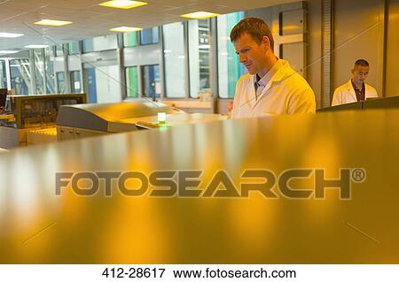 Workers among printers in printing plant View Large Photo Image Stock Photo - Workers among printers in printing plant. Fotosearch