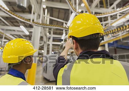Workers discussing printing press conveyor belts overhead View Large Photo Image Stock Image - Workers discussing printing press conveyor belts overhead. Fotosearch