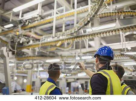 Workers discussing winding printing press conveyor belts overhead View Large Photo Image Picture - Workers discussing winding printing press conveyor belts overhead. Fotosearch