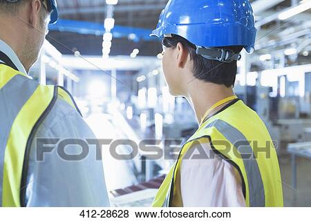 Stock Photo - Workers in reflective clothing and hard-hat in factory. Fotosearch