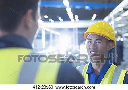 Workers in reflective clothing talking in factory View Large Photo Image Stock Image - Workers in reflective clothing talking in factory. Fotosearch