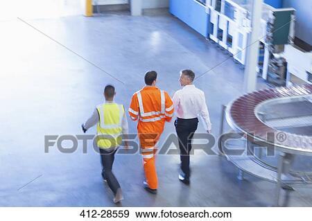 Workers in reflective clothing walking in factory View Large Photo Image Stock Photo - Workers in reflective clothing walking in factory. Fotosearch