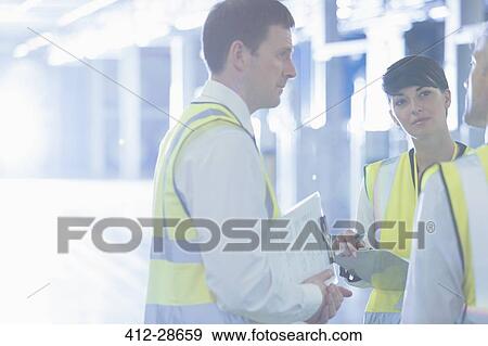 Workers in reflective with clipboards talking in factory View Large Photo Image Stock Photo - Workers in reflective with clipboards talking in factory. Fotosearch