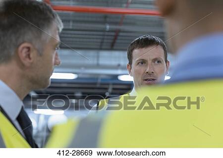 Workers talking in factory View Large Photo Image Stock Photo - Workers talking in factory. Fotosearch