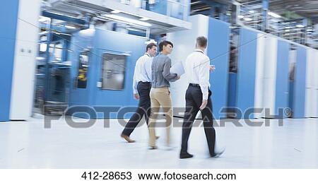 Stock Image - Workers walking in factory. Fotosearch