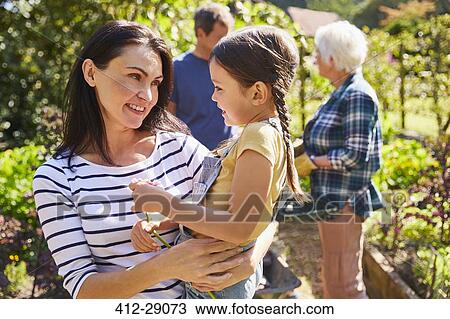 Affectionate mother holding daughter in sunny garden View Large Photo Image Stock Image - Affectionate mother holding daughter in sunny garden. Fotosearch