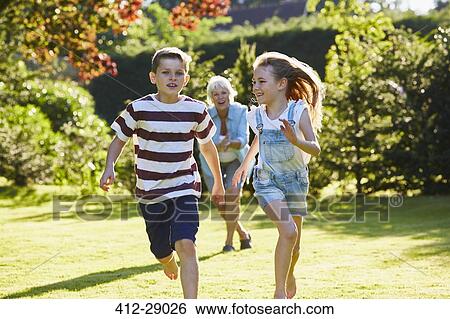 Stock Photograph - Brother and sister running in sunny garden. Fotosearch