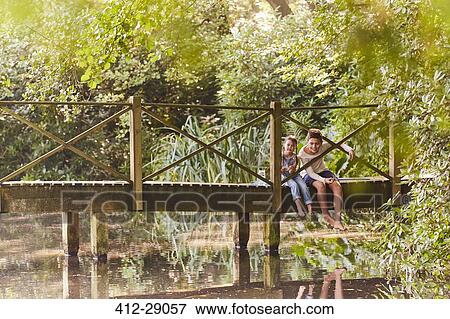 Brother and sister sitting on footbridge in park with trees View Large Photo Image Stock Photo - Brother and sister sitting on footbridge in park with trees. Fotosearch