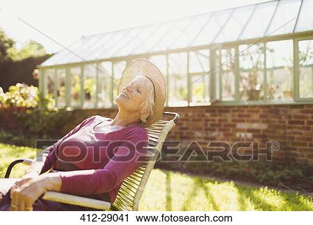 Carefree senior woman relaxing outside sunny greenhouse View Large Photo Image Stock Image - Carefree senior woman relaxing outside sunny greenhouse. Fotosearch