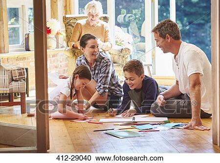 Stock Image - Family coloring on floor in sun room. Fotosearch