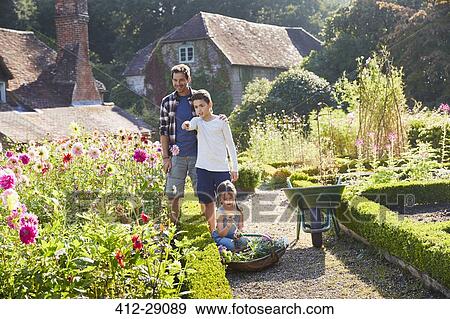 Stock Photo - Family picking flowers in sunny garden. Fotosearch