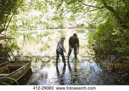 Father and son fishing with nets in forest pond View Large Photo Image Stock Image - Father and son fishing with nets in forest pond. Fotosearch