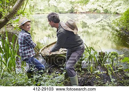 Father and son pulling boat to shore in pond View Large Photo Image Stock Image - Father and son pulling boat to shore in pond. Fotosearch