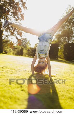 Girl doing handstand in sunny garden View Large Photo Image Stock Photo - Girl doing handstand in sunny garden. Fotosearch