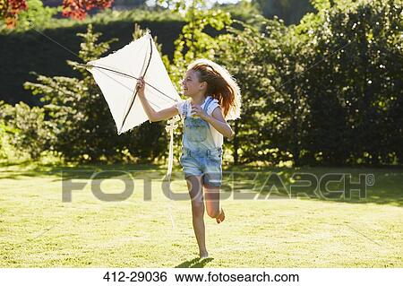 Stock Photograph - Girl running with kite in sunny garden. Fotosearch
