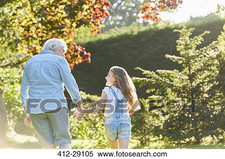 Grandmother and granddaughter holding hands and walking in sunny garden View Large Photo Image Stock Photography - Grandmother and granddaughter holding hands and walking in sunny garden. Fotosearch