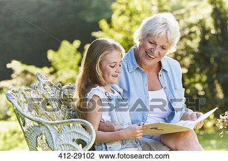 Grandmother reading with granddaughter on garden bench View Large Photo Image Stock Image - Grandmother reading with granddaughter on garden bench. Fotosearch