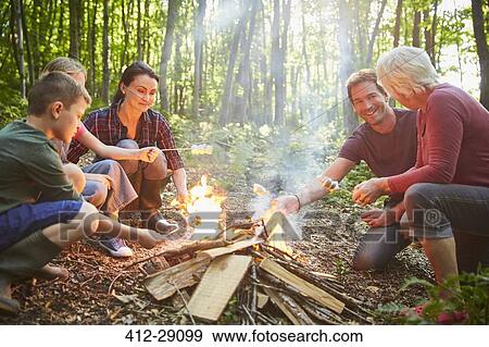 Multi-generation family roasting marshmallows at campfire in forest View Large Photo Image Stock Photo - Multi-generation family roasting marshmallows at campfire in forest. Fotosearch