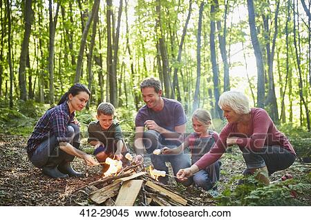 Multi-generation family roasting marshmallows at campfire in forest View Large Photo Image Stock Photography - Multi-generation family roasting marshmallows at campfire in forest. Fotosearch