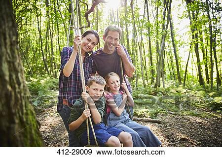Portrait smiling family at rope swing in woods View Large Photo Image Stock Photo - Portrait smiling family at rope swing in woods. Fotosearch