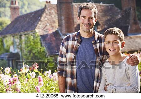 Stock Photography - Portrait smiling father and son in sunny flower garden. Fotosearch