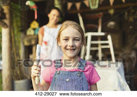 Stock Photo - Portrait smiling girl holding paintbrush. Fotosearch