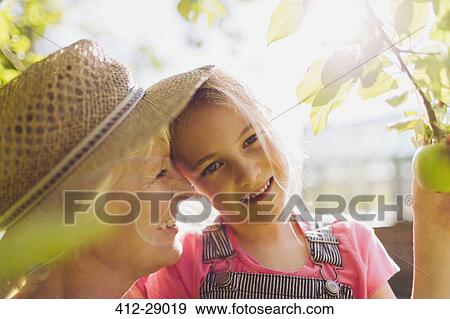 Stock Photo - Portrait smiling granddaughter with grandmother in sunny garden. Fotosearch