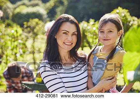 Portrait smiling mother and daughter hugging in sunny garden View Large Photo Image Stock Image - Portrait smiling mother and daughter hugging in sunny garden. Fotosearch