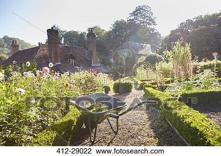Wheelbarrow in sunny formal garden View Large Photo Image Stock Image - Wheelbarrow in sunny formal garden. Fotosearch