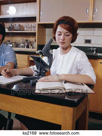 1960 1960S Teen Girl Young Woman Study Wtih Open Textbook Seated At Microscope Science Class High School Retro View Large Photo Image Stock Photo - 1960 1960S Teen Girl Young Woman Study Wtih Open Textbook Seated At Microscope Science Class High School Retro . Fotosearch