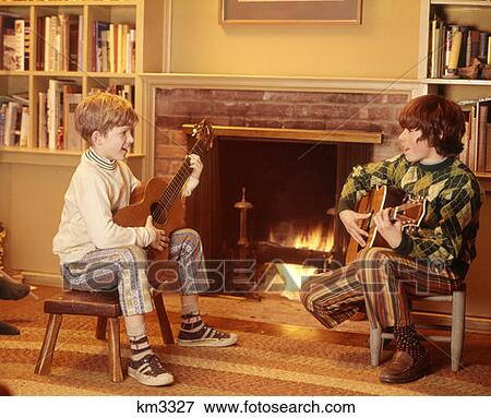 1970 1970S 2 Boys Front Fireplace Play Playing Strumming Guitars Children Boy Child Music Living Room Stools View Large Photo Image Stock Photo - 1970 1970S 2 Boys Front Fireplace Play Playing Strumming Guitars Children Boy Child Music Living Room Stools . Fotosearch