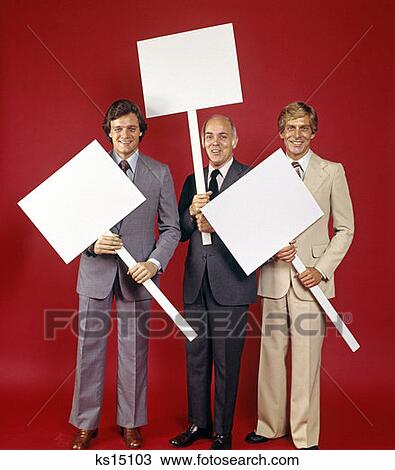Stock Image - 1970 1970S 3 Businessmen Full Figure Holding Blank Signs Posters Placards Red Background Man Men Business Retro . Fotosearch