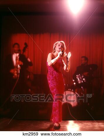 1970 1970S Blonde Woman Singer Long Pink Red Gown White Gloves Singing On Stage Backup Musicians Vocalist Singers View Large Photo Image Stock Photo - 1970 1970S Blonde Woman Singer Long Pink Red Gown White Gloves Singing On Stage Backup Musicians Vocalist Singers . Fotosearch