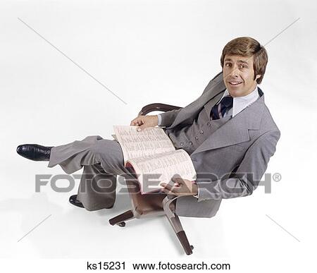 1970 1970S Businessman Gray 3 Piece Suit Looking Up Business Book Directory Lap Sitting In Office Chair Man Men Retro View Large Photo Image Stock Image - 1970 1970S Businessman Gray 3 Piece Suit Looking Up Business Book Directory Lap Sitting In Office Chair Man Men Retro. Fotosearch