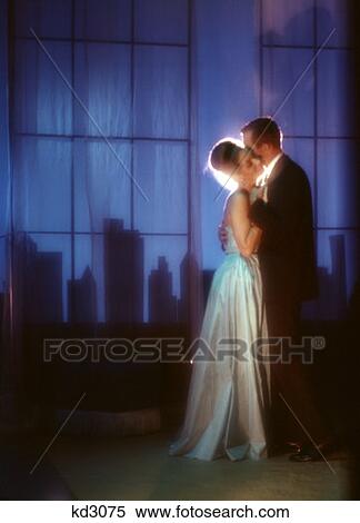 Stock Photography - 1970 1970S Couple Dancing Formal Woman Long White Gown Night City Skyline Dance Date Rooftop Penthouse Nightclub Romance . Fotosearch