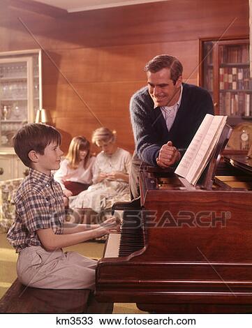 1970 1970S Family Living Room Boy Son Playing Piano Father Listening Mother Girl Daughter Couch Background Families View Large Photo Image Stock Image - 1970 1970S Family Living Room Boy Son Playing Piano Father Listening Mother Girl Daughter Couch Background Families . Fotosearch