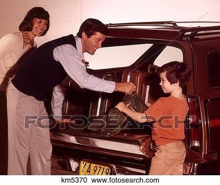 Stock Image - 1970 1970S Family Loading Trunk Station Wagon Road Trip Luggage Suitcases Boy Son Mother Father Man Woman Families . Fotosearch