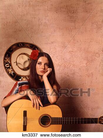 1970 1970S Moody Serious Latin Spanish Hispanic Woman Leaning On Guitar Mexican Sombrero On Wall View Large Photo Image Stock Photo - 1970 1970S Moody Serious Latin Spanish Hispanic Woman Leaning On Guitar Mexican Sombrero On Wall . Fotosearch