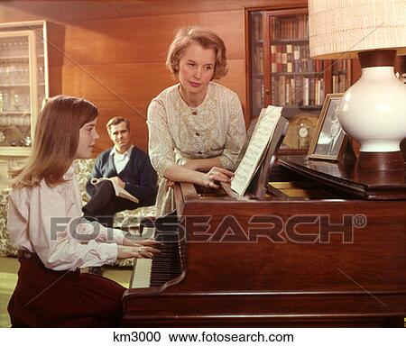1970 1970S Mother Turning Page Music Girl Daughter Plays Piano Living Room Father Couch Man Woman Girl Pianos View Large Photo Image Stock Image - 1970 1970S Mother Turning Page Music Girl Daughter Plays Piano Living Room Father Couch Man Woman Girl Pianos . Fotosearch