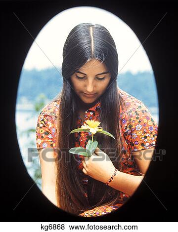 1970 1970S Oval Vignette Teen Teenage Teenager Girl Moody Expression Holding Yellow Flower Retro View Large Photo Image Stock Photo - 1970 1970S Oval Vignette Teen Teenage Teenager Girl Moody Expression Holding Yellow Flower Retro . Fotosearch