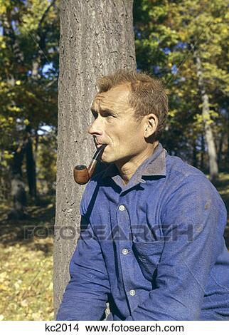 Picture - 1970 1970S Retro Man Leaning On A Tree Smoking Pipe Outdoors. Fotosearch