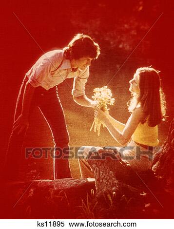 1970 1970S Romantic Couple Man Giving Woman Flower Bouquet Red Linen Filter Texture Soft Focus Romance Retro View Large Photo Image Stock Photography - 1970 1970S Romantic Couple Man Giving Woman Flower Bouquet Red Linen Filter Texture Soft Focus Romance Retro. Fotosearch
